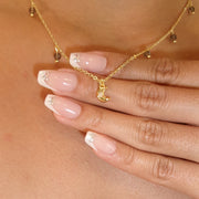 Close-up of a hand wearing a gold ring and bracelet on a beige background
